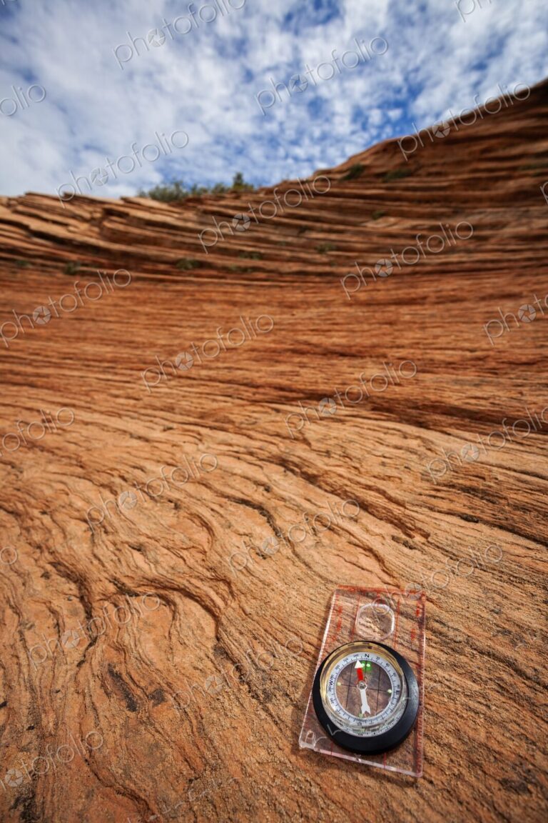 A clear compass rests on weathered red sandstone in Zion National Park, symbolizing…