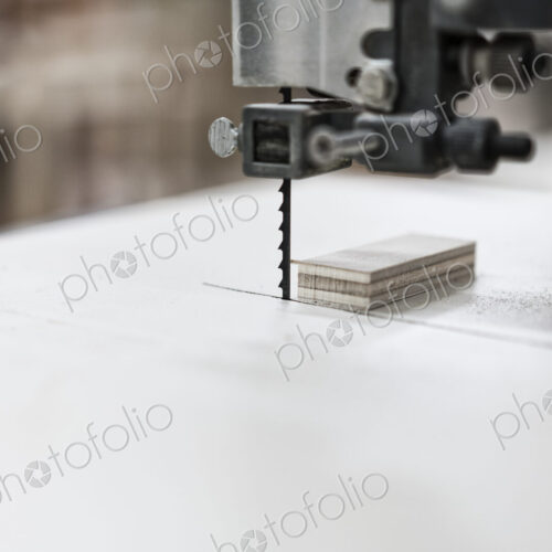 A close up of a band saw used to cut small pieces of wood in a cabinet shop. A close up of a band saw used to cut small pieces of wood in a cabinet shop.