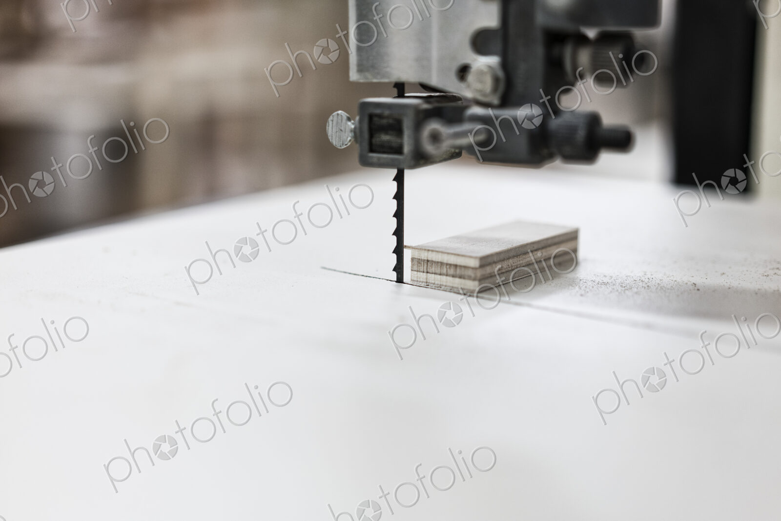 A close up of a band saw used to cut small pieces of wood in a cabinet shop.