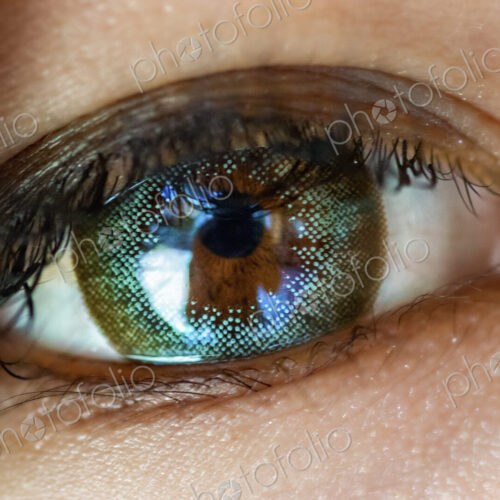 A close up of a human eye, with a content lens in place. A reflection of an object or… A close up of a human eye, with a content lens in place. A reflection of an object or…