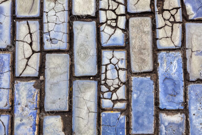 A close-up view of cracked blue cobblestones lining the historic streets of Old San…