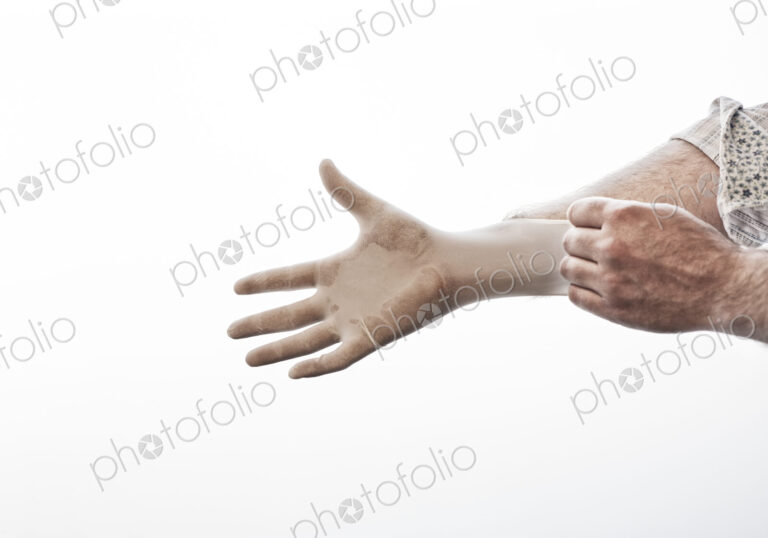 A closeup of a hand pulling on a medical examination glove.