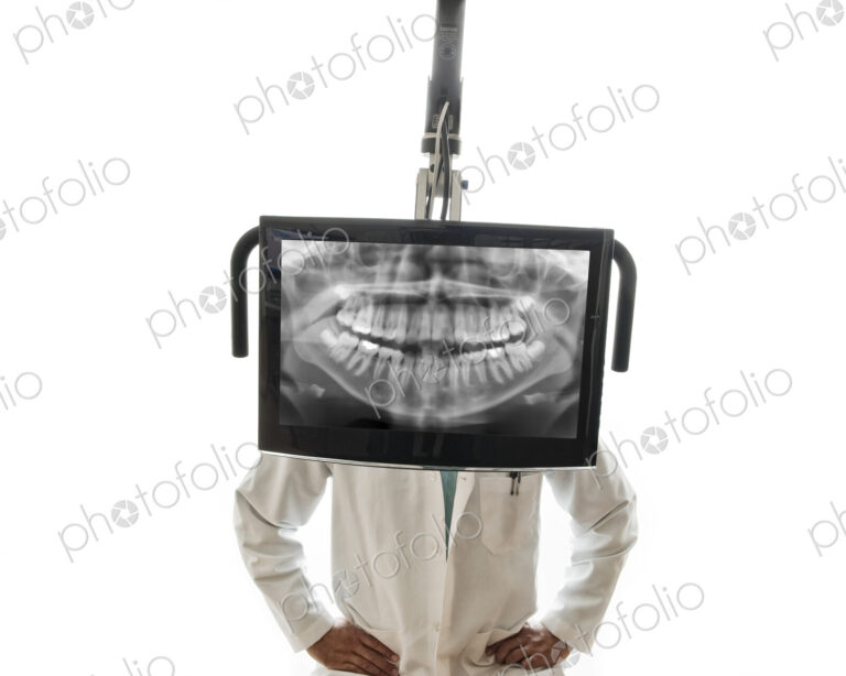 A closeup of a monitor with a dental x-ray and a dentist standing behind the monitor.