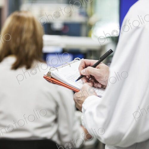 A closeup of hands taking notes in a technical reserach and development site.