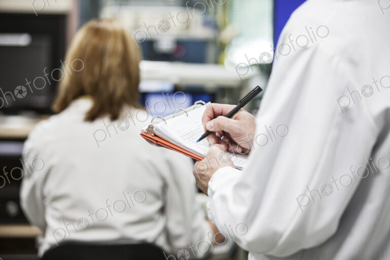 A closeup of hands taking notes in a technical reserach and development site.