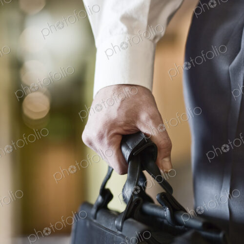A closeup of the hand of a businessman holding a brief case.