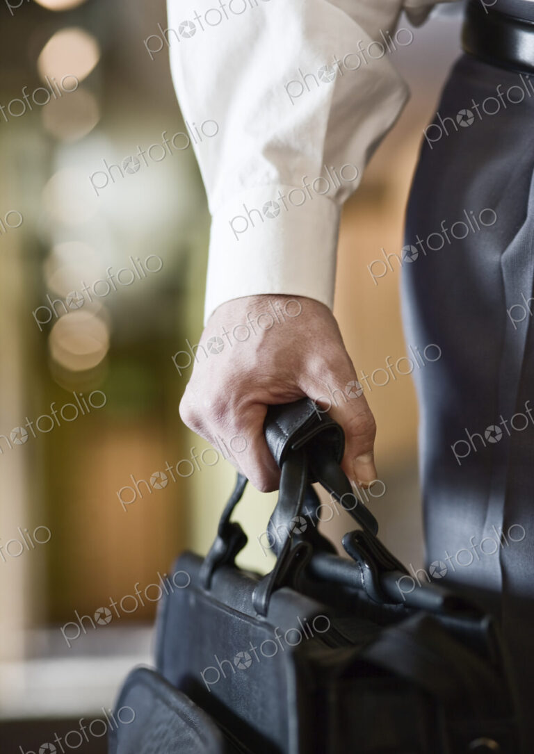 A closeup of the hand of a businessman holding a brief case.