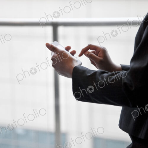 A closeup of the hands of a businesswoman texting on a cell phone.