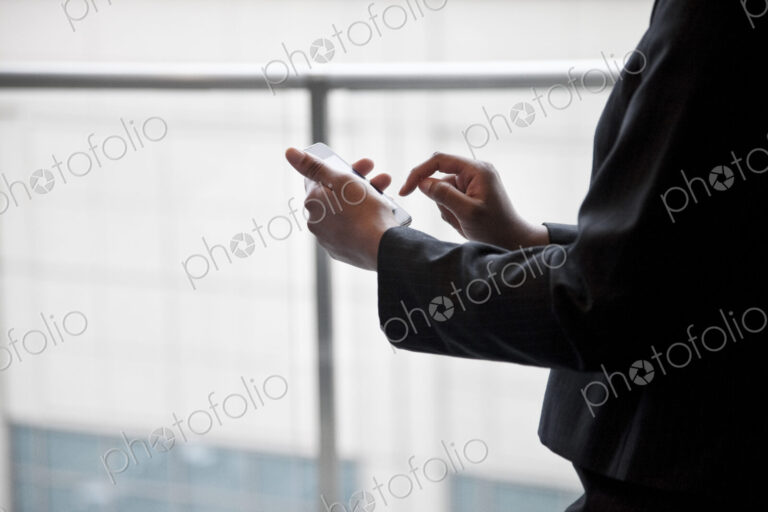 A closeup of the hands of a businesswoman texting on a cell phone.