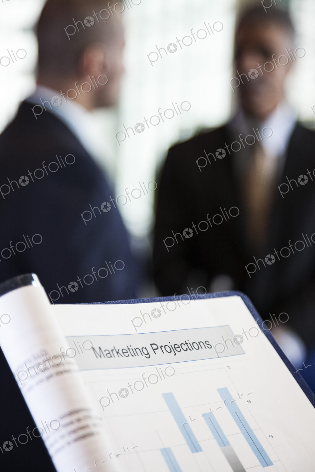 A closeup view of a business report with two businessmen in the background.