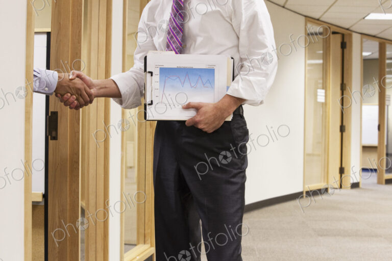 A closeup view of two business people shaking hands in an office space.