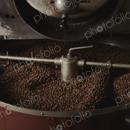 A coffee shop. A metal drum with roasting coffee beans and a central paddle.