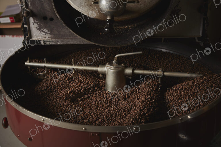 A coffee shop. A metal drum with roasting coffee beans and a central paddle.
