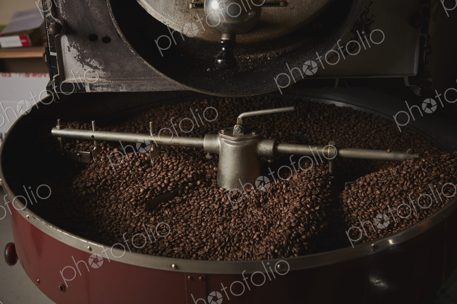 A coffee shop. A metal drum with roasting coffee beans and a central paddle.