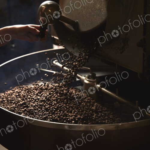 A coffee shop. A metal drum with roasting coffee beans and a central paddle.