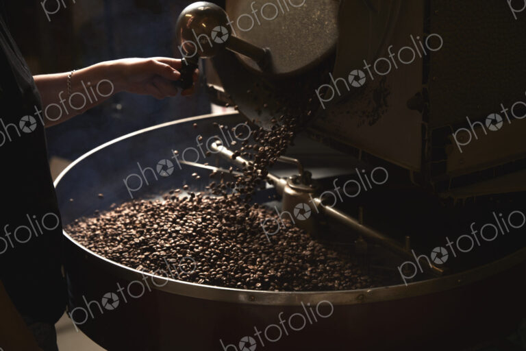 A coffee shop. A metal drum with roasting coffee beans and a central paddle.