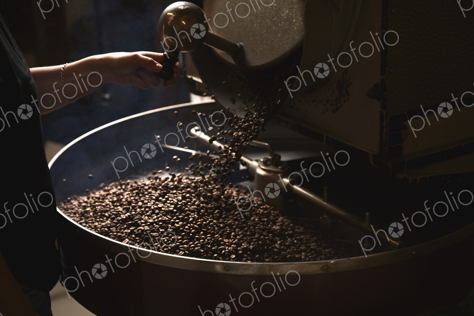 A coffee shop. A metal drum with roasting coffee beans and a central paddle.