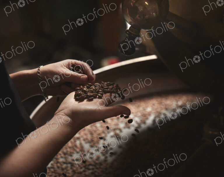A coffee shop. A person holding a handful of fresh coffee beans.