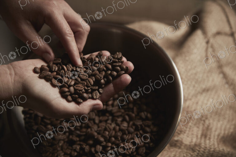 A coffee shop. A person holding a handful of fresh roasted coffee beans.