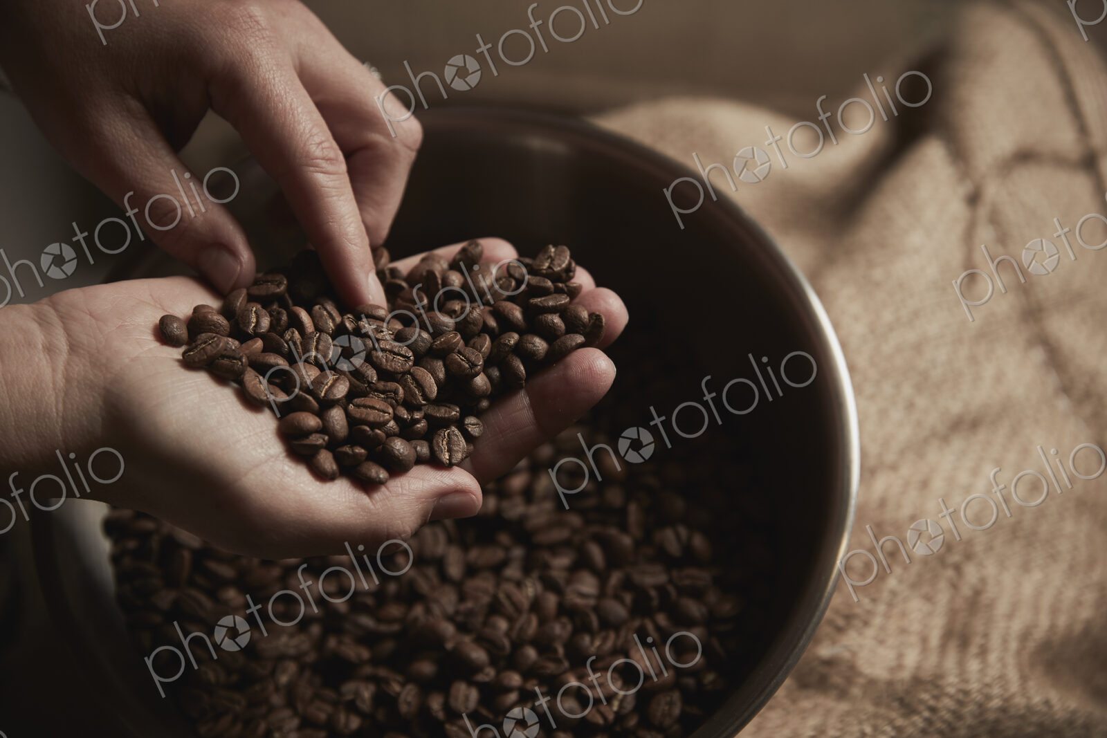 A coffee shop. A person holding a handful of fresh roasted coffee beans.