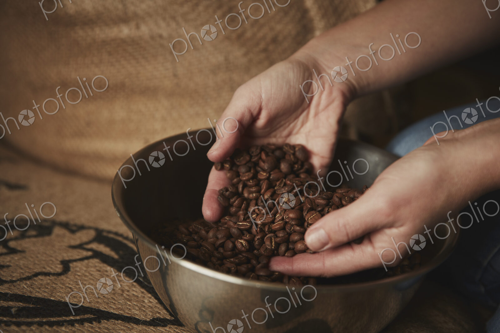 A coffee shop. A person holding fresh roasted beans in her hands.
