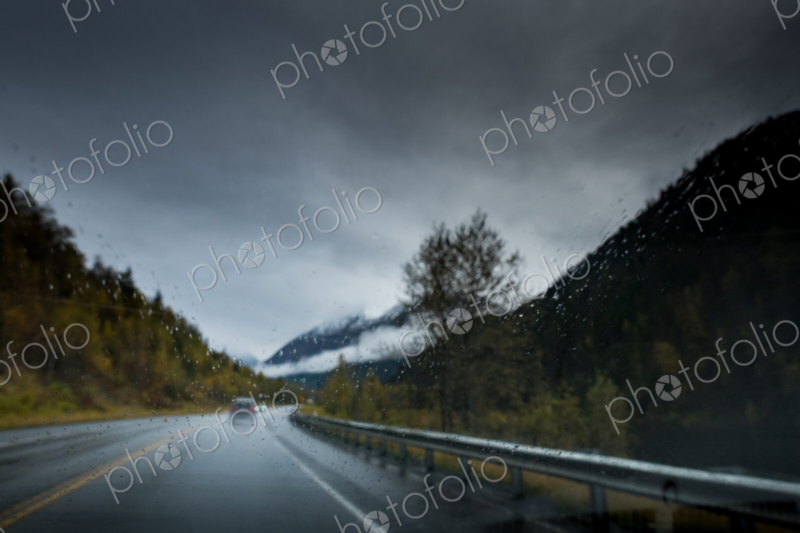 A cold wet day, low light, rain falling on the road, driver point of view.