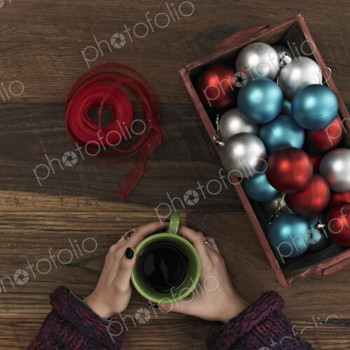 A collection of blue, red and silver ornaments and red ribbon in a box on a wooden… A collection of blue, red and silver ornaments and red ribbon in a box on a wooden…