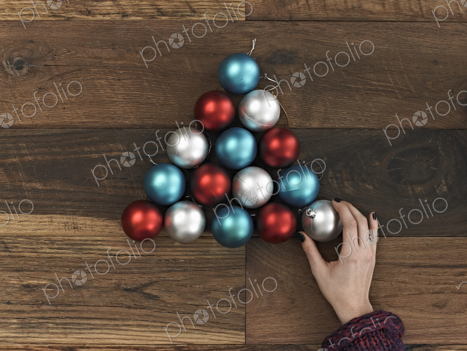 A collection of blue, red and silver ornaments arranged in a triangular shape on a…