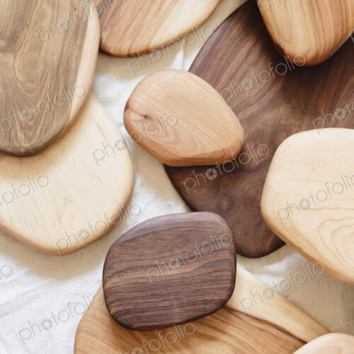 A collection of small smooth turned wooden objects of different colours and wood grain…