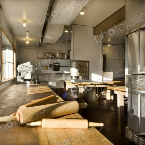 A commercial bakery with row of ovens and preparation area, a wooden board with three… A commercial bakery with row of ovens and preparation area, a wooden board with three…