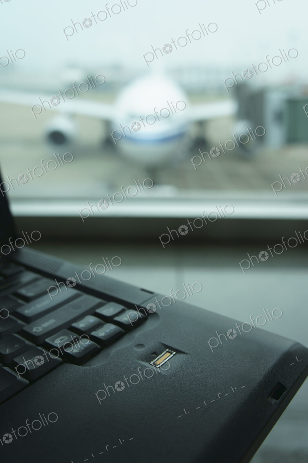 A computer laptop on a surface,in front of a window. Airport apron and aircraft seen…