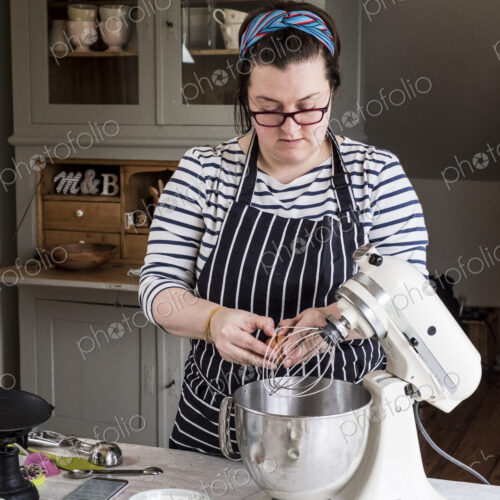 A cook in her kitchen breaking eggs and weighing ingredients for chocolate brownies. A cook in her kitchen breaking eggs and weighing ingredients for chocolate brownies.
