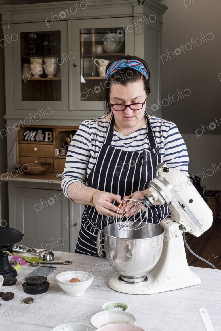 A cook in her kitchen breaking eggs and weighing ingredients for chocolate brownies.