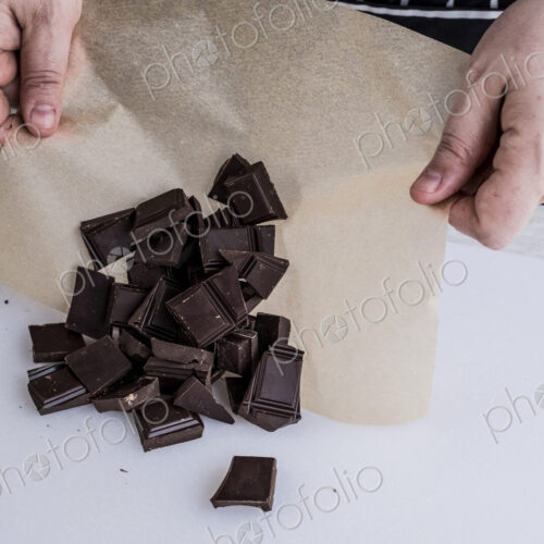 A cook with weighed chocolate pieces on greaseproof paper. A cook with weighed chocolate pieces on greaseproof paper.