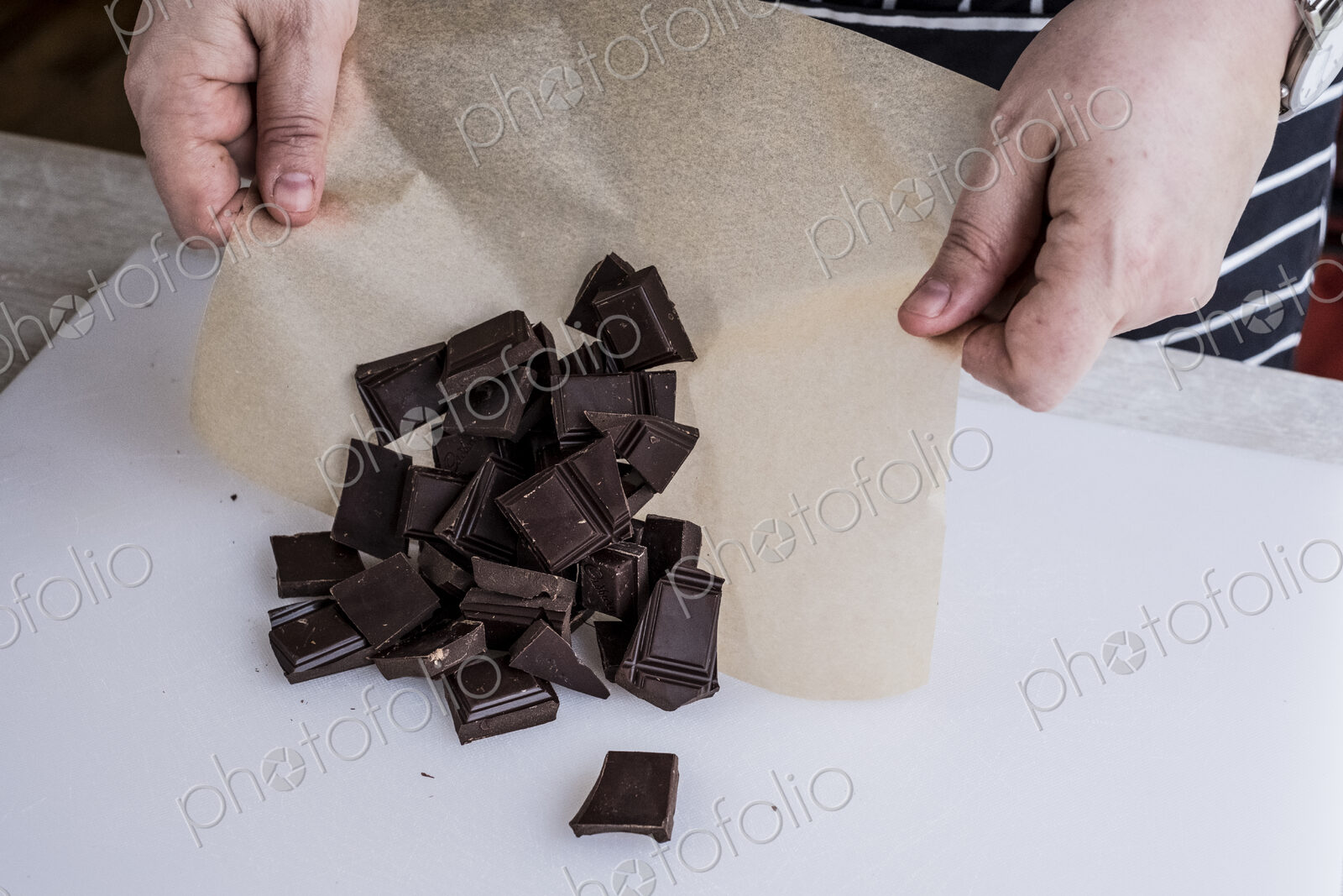 A cook with weighed chocolate pieces on greaseproof paper.