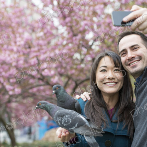 A couple, a man and woman, in the park, taking a selfy, self portrait with a mobile…