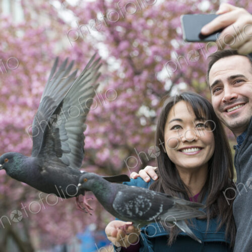 A couple, a man and woman, in the park, taking a selfy, self portrait with a mobile…