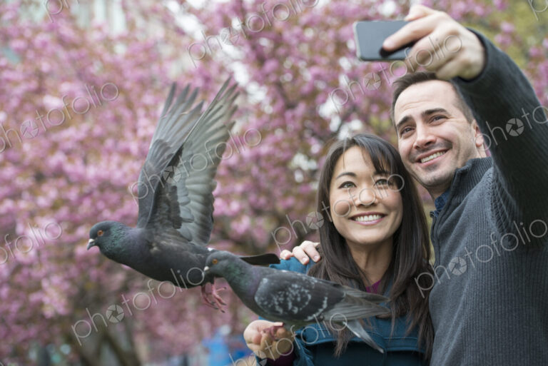 A couple, a man and woman, in the park, taking a selfy, self portrait with a mobile…