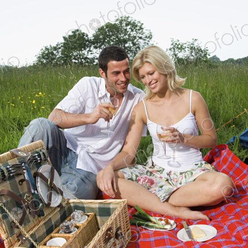 A couple, a man and woman seated having a picnic. A blue tent. Camping. A couple, a man and woman seated having a picnic. A blue tent. Camping.