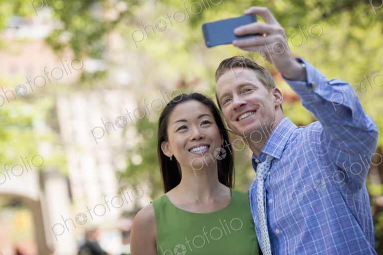 A couple, a man and woman taking a selfy with a smart phone.