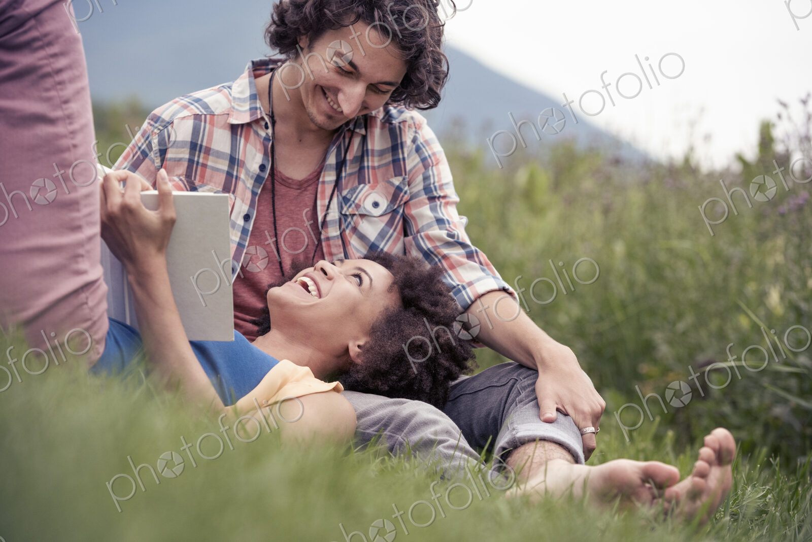 A couple, a woman with an open book looking up at a man smiling at him.