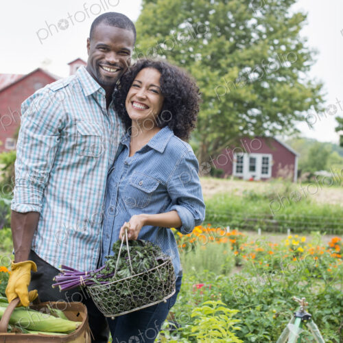 A couple carrying baskets of freshly harvested corn on the cob