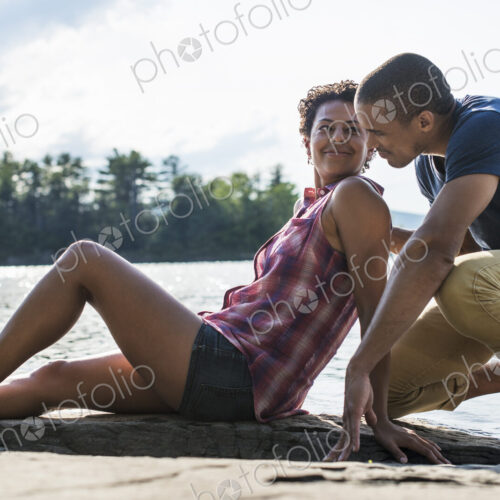 A couple close together by a lake in summer. A couple close together by a lake in summer.