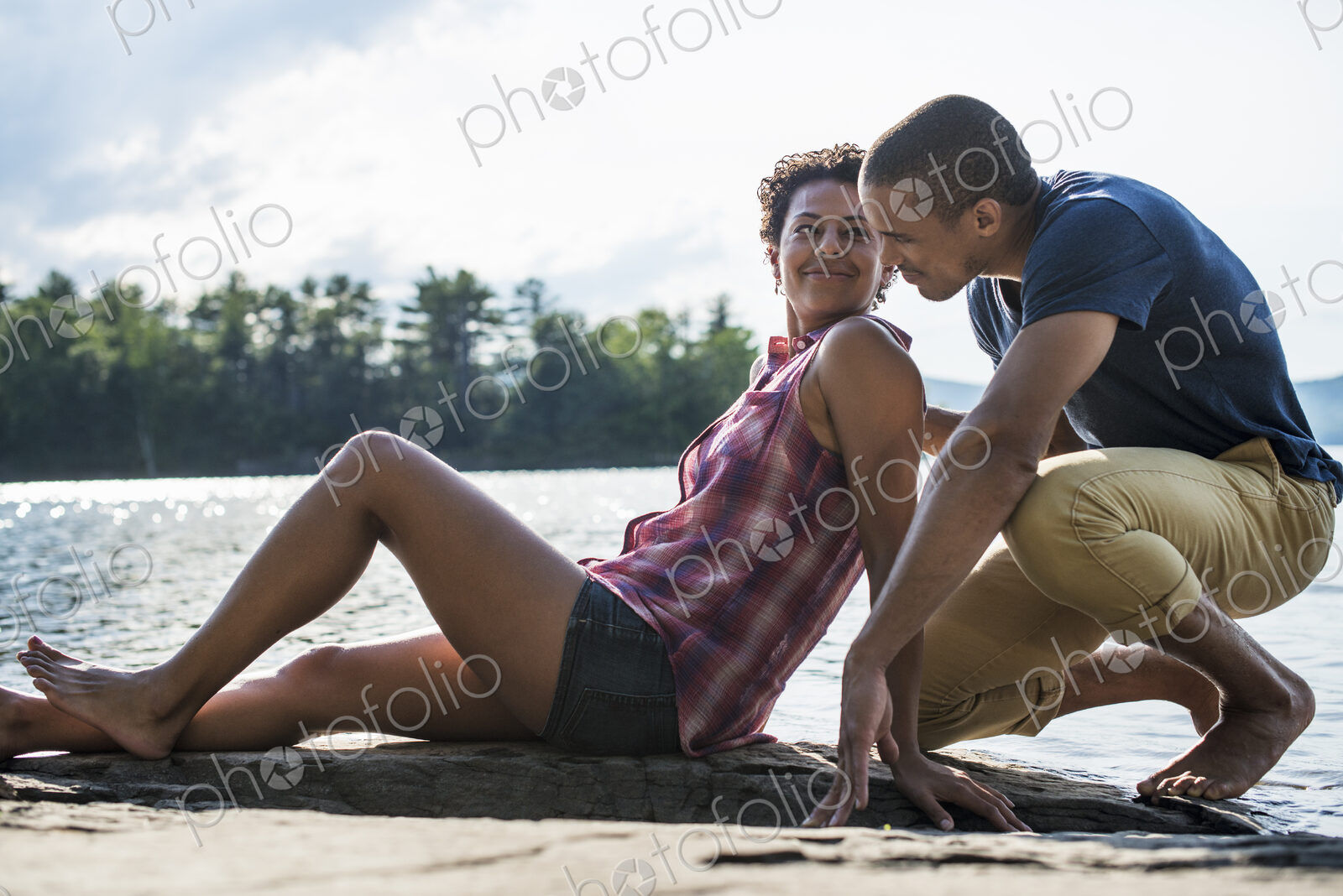 A couple close together by a lake in summer.