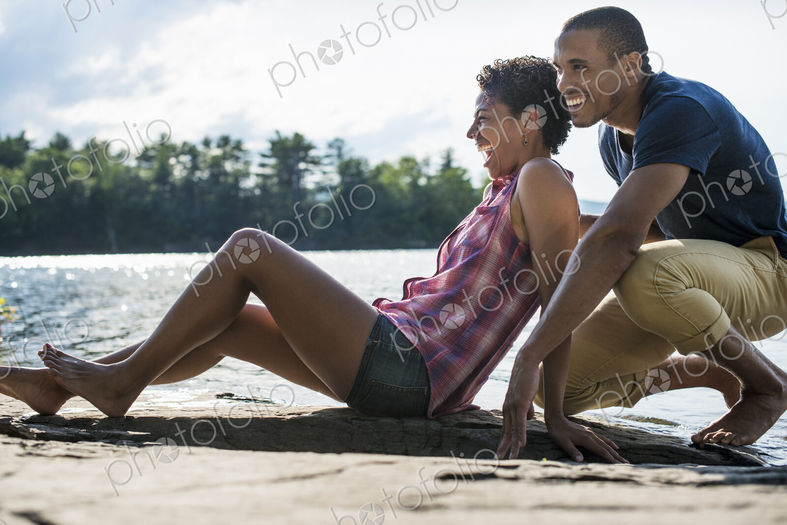 A couple close together by a lake in summer.