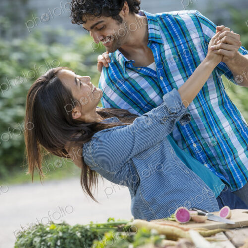 A couple embracing and dancing in a garden. A couple embracing and dancing in a garden.