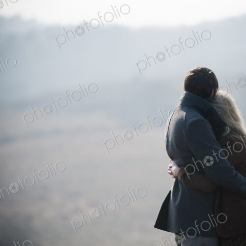 A couple embracing. Standing in a field in the country.