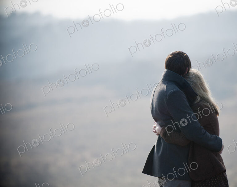 A couple embracing. Standing in a field in the country.