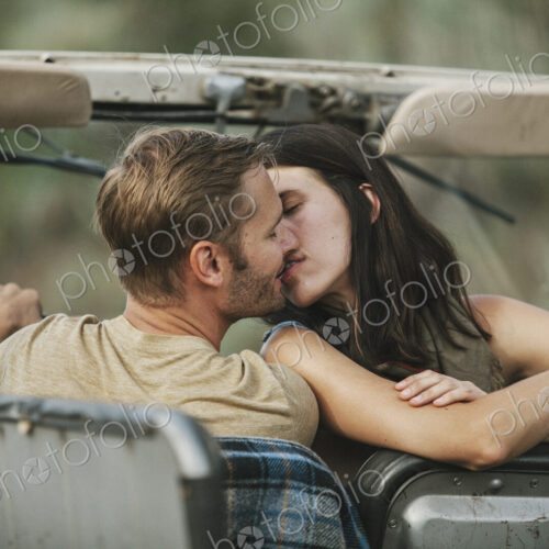 A couple in an open top jeep kissing. A couple in an open top jeep kissing.