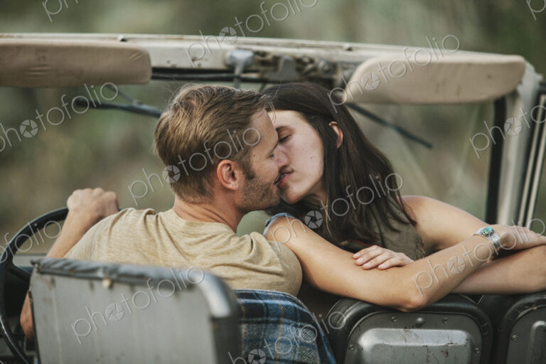 A couple in an open top jeep kissing.